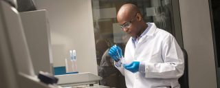 Man wearing white lab coat, goggles in laboratory setting