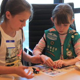 Two Girls Scouts explore the benefits of assembly-line manufacturing with mini Lego cars